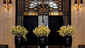 Um hall com um candelabro, arandelas pretas, um balcão de recepção preto e um sofá estampado com onças.