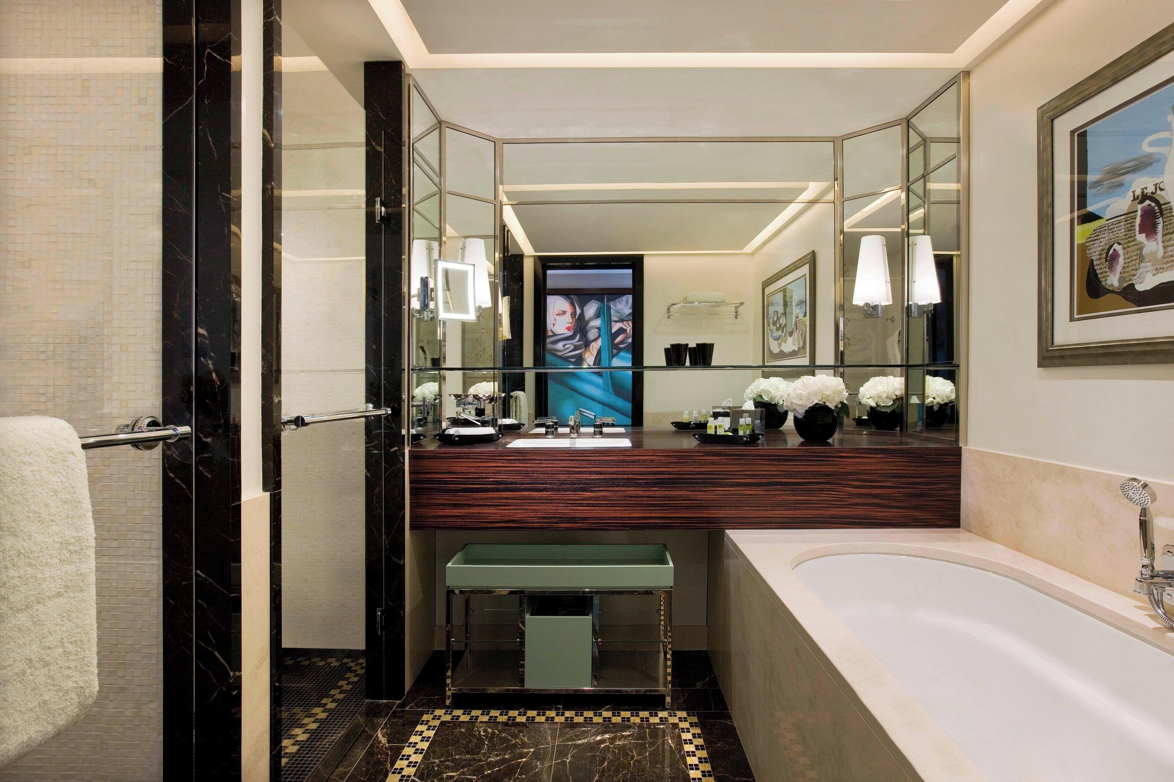 Une salle de bain moderne dotée d’un grand miroir, d’une baignoire, d’un meuble-lavabo et d’un espace douche.