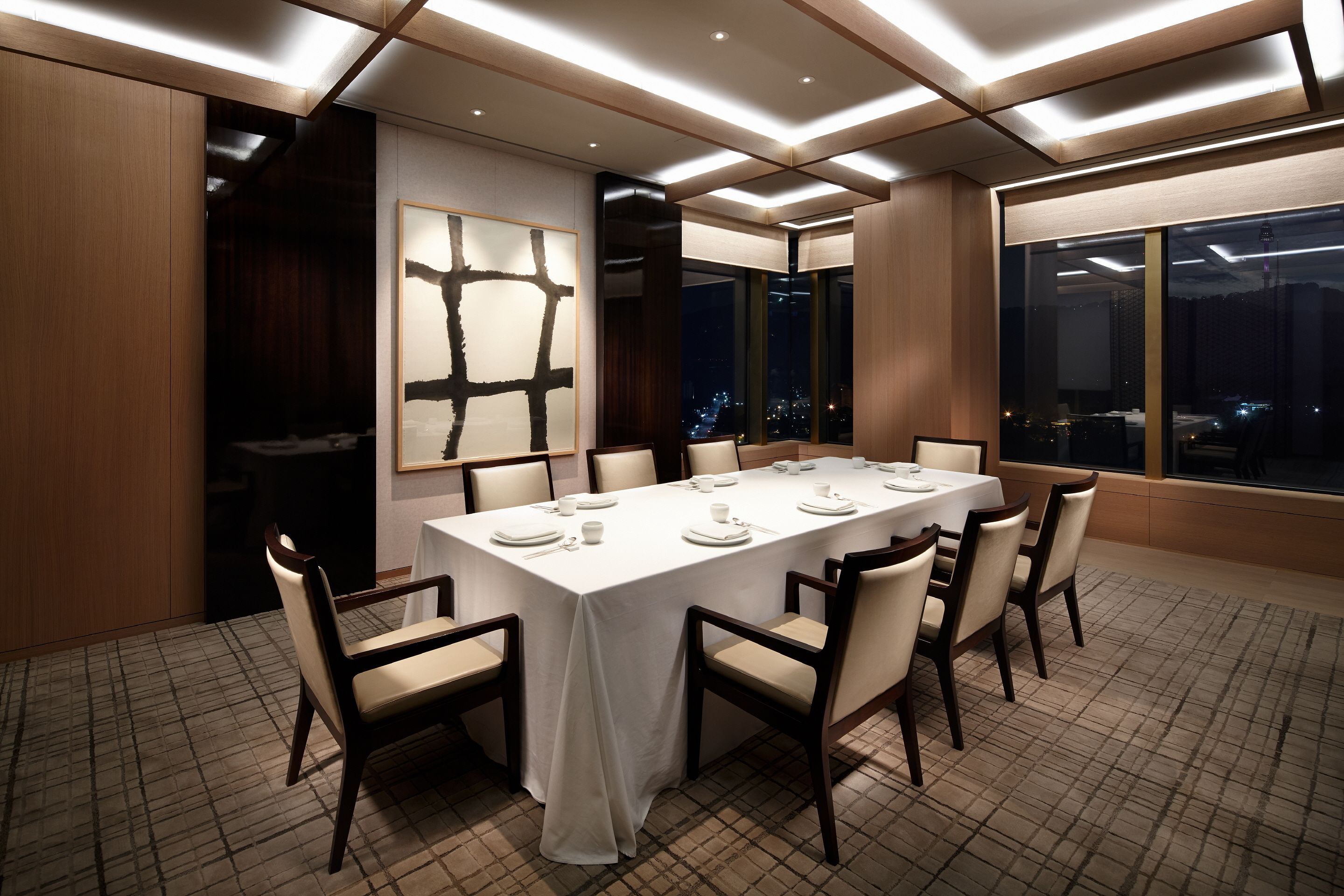 A modern dining room with a rectangular table set for six, surrounded by chairs.