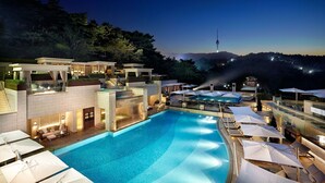 A modern hotel with a swimming pool, outdoor seating, and a view of a tower in the background. - The Shilla Seoul (Seoul)