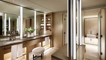 A modern bathroom with a large mirror, dual sinks, and a vanity with storage shelves.
