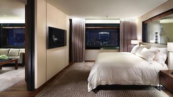 Ein modernes Hotelzimmer mit einem großen Bett, Stadtblick, einem Flachbildfernseher und einer Sitzecke mit Couchtisch.