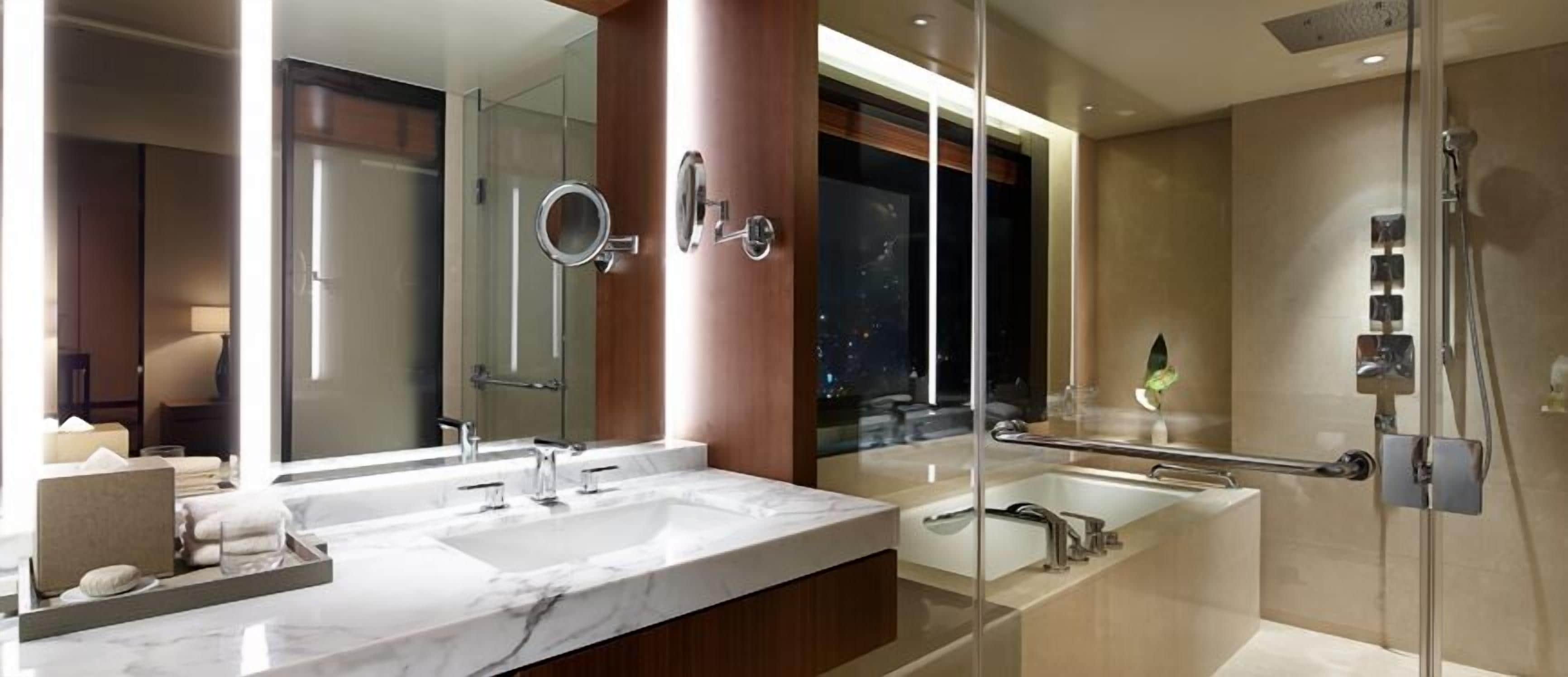 Un baño moderno con dos lavamanos, un espejo grande, una bañera y una ducha.