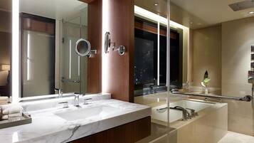 Un baño moderno con dos lavamanos, un espejo grande, una bañera y una ducha.