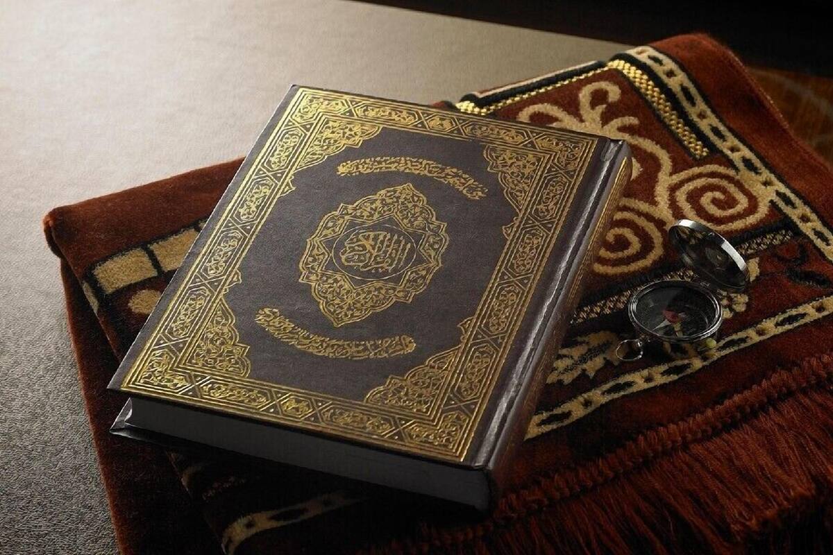 Um livro com detalhes em dourado elaborado em capa escura, apoiado em tecido estampado.