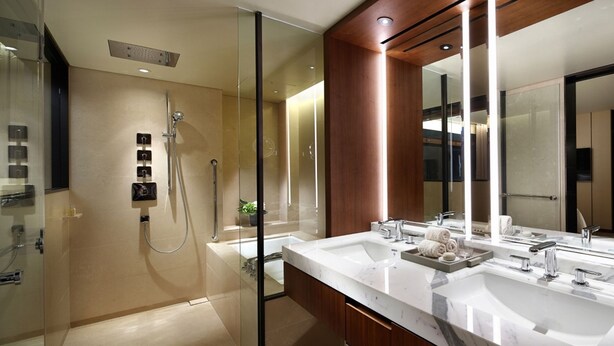 A modern bathroom with a glass-enclosed shower, a large mirror, and a marble countertop with two sinks. - The Shilla Seoul (Seoul)