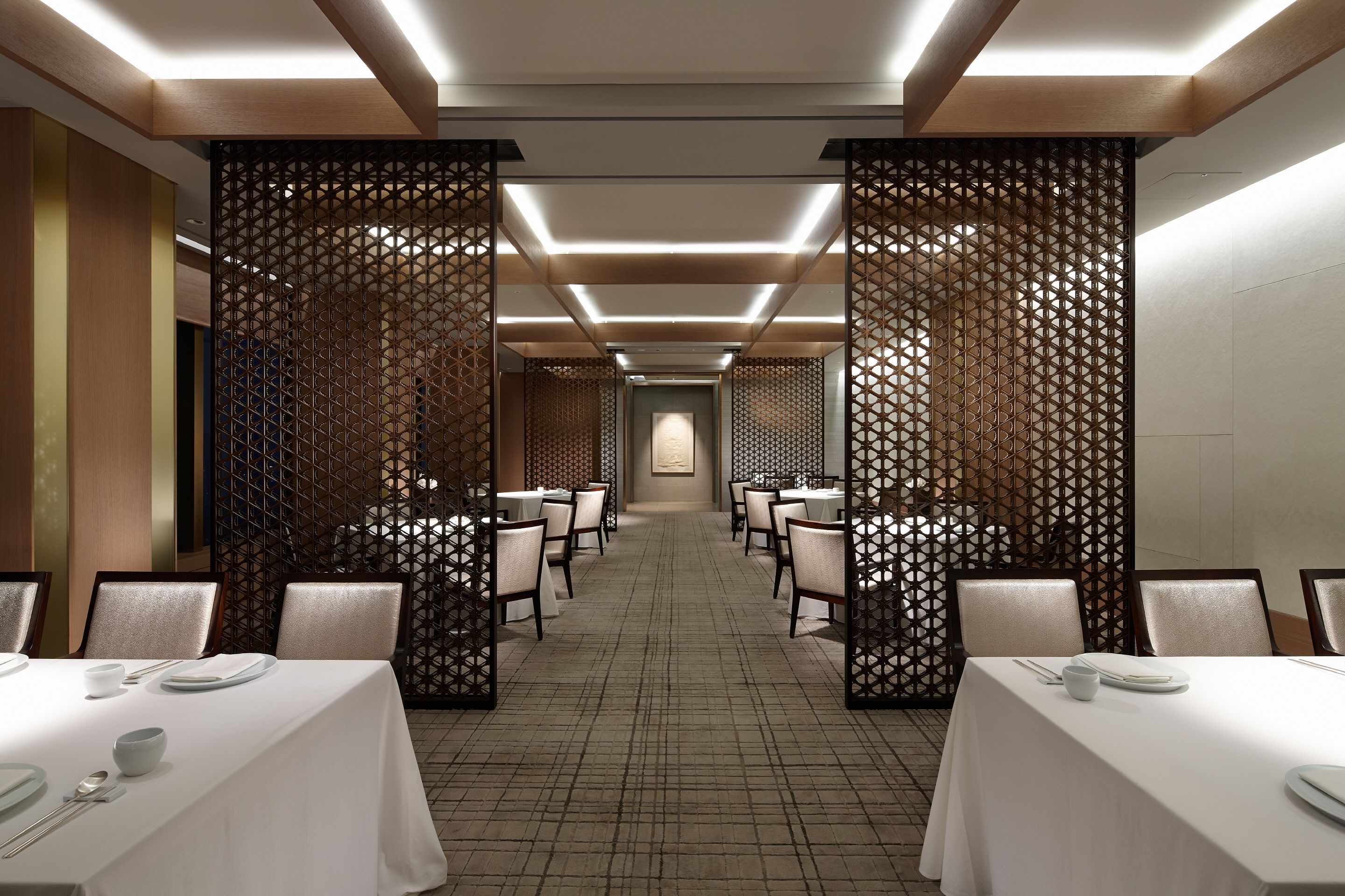 Comedor de hotel con varias mesas, sillas y un separador decorativo.