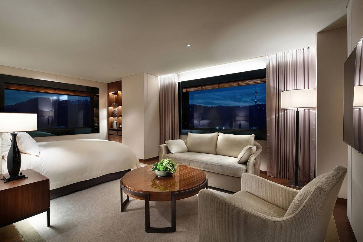 Quarto de hotel com uma cama, um sofá, uma mesa de centro e uma televisão.