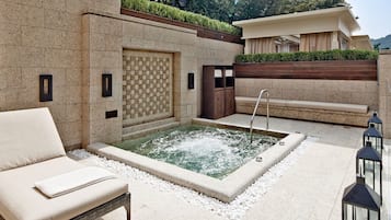 Un espacio de spa con un jacuzzi, una silla de descanso y un banco de madera.