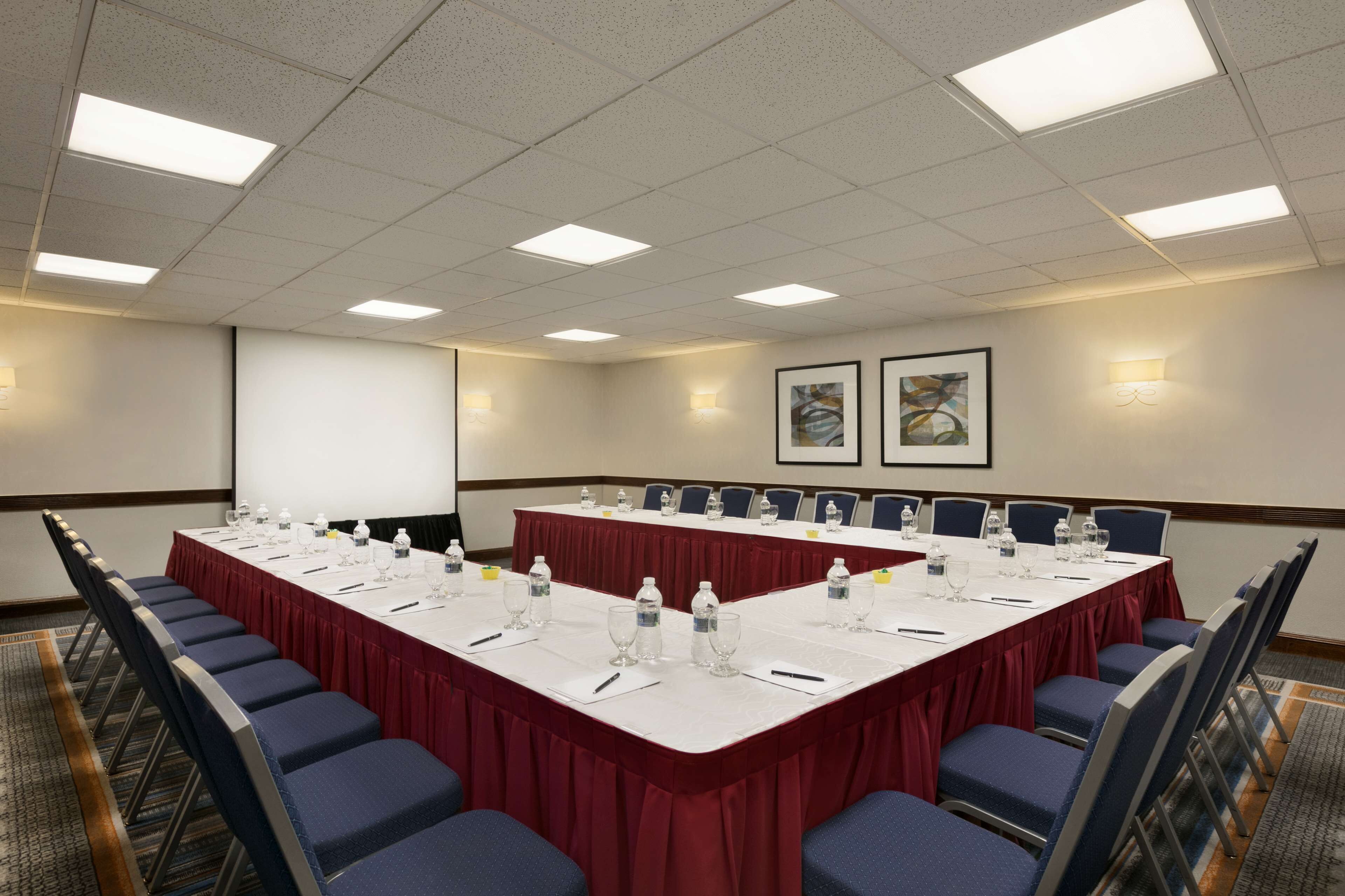 A conference room with a long table, chairs, and a projector screen.