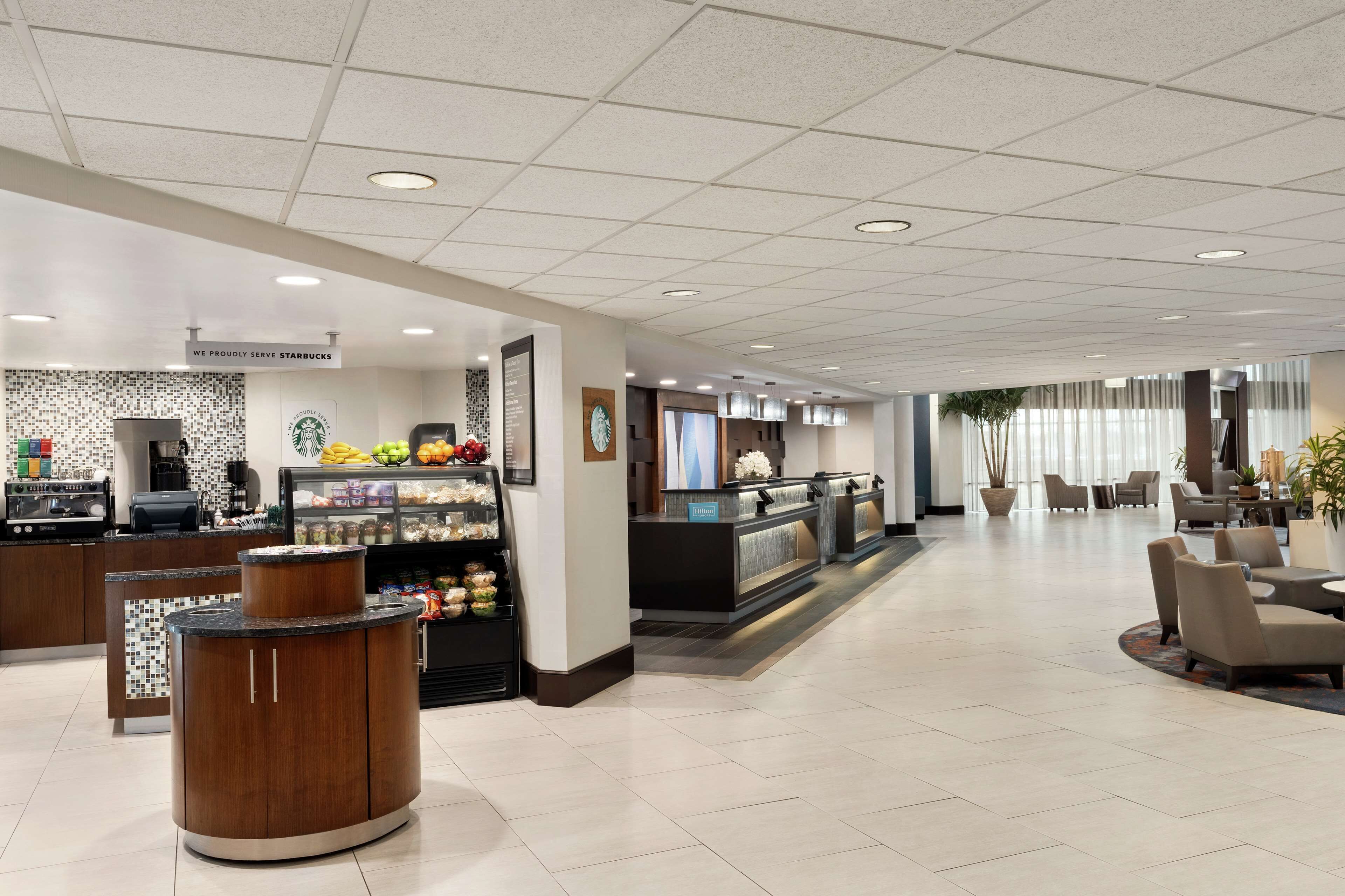 Un'ampia hall con un bancone Starbucks, area salotto e reception.