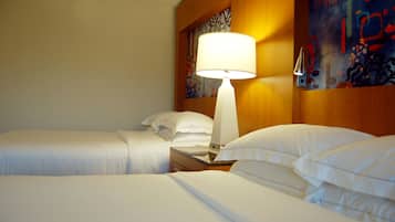 A hotel room with two beds, a nightstand with a lamp, and artwork on the walls.