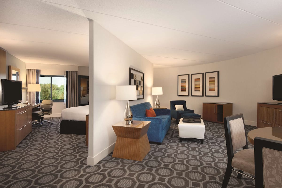 Una habitación de hotel con cama, escritorio, silla, sofá y televisor.
