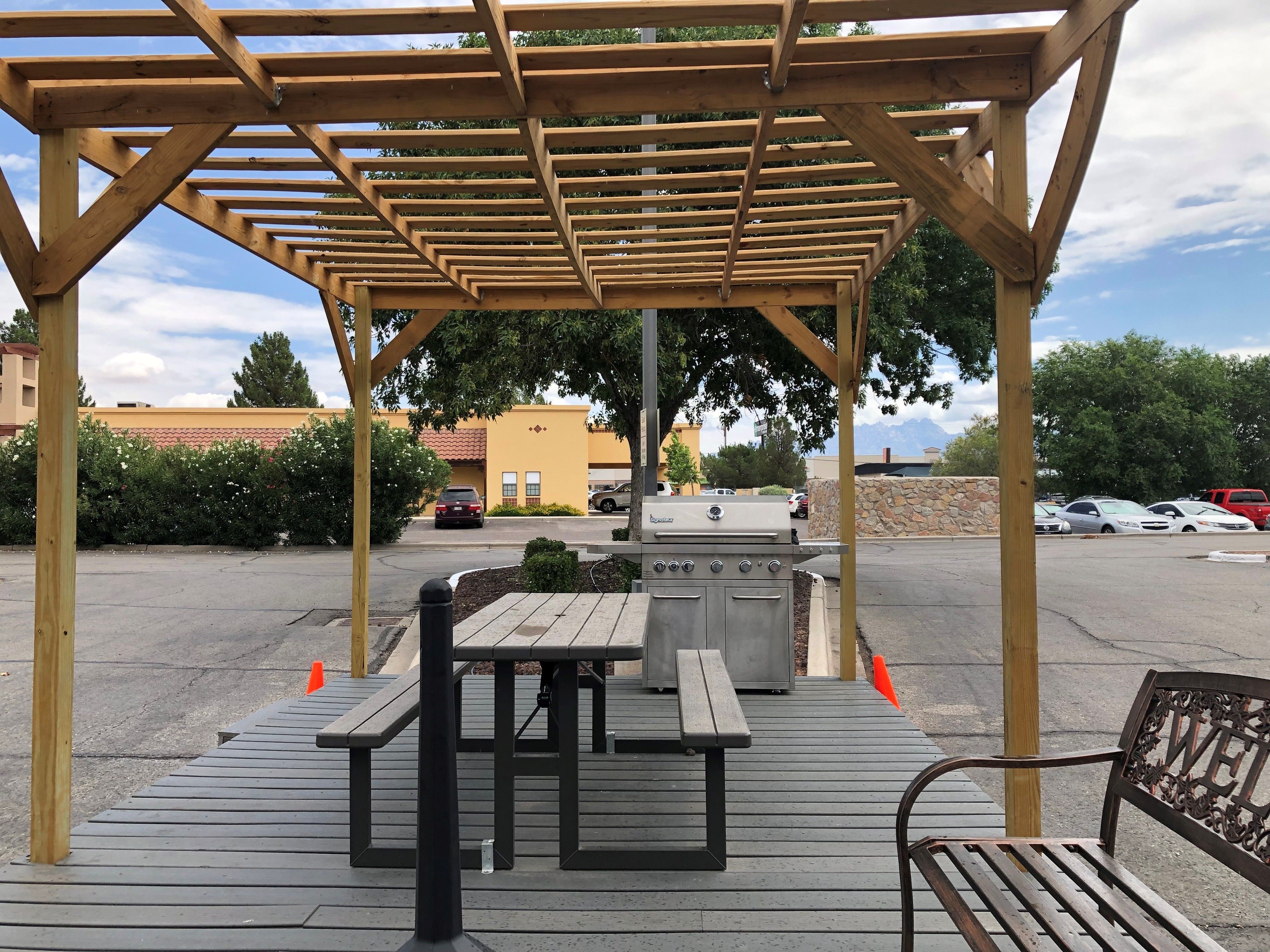 Un espace extérieur abrité comprenant un barbecue, des tables de pique-nique et des bancs.