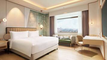 Une chambre d’hôtel moderne avec un grand lit, un bureau et une vue sur la ville.
