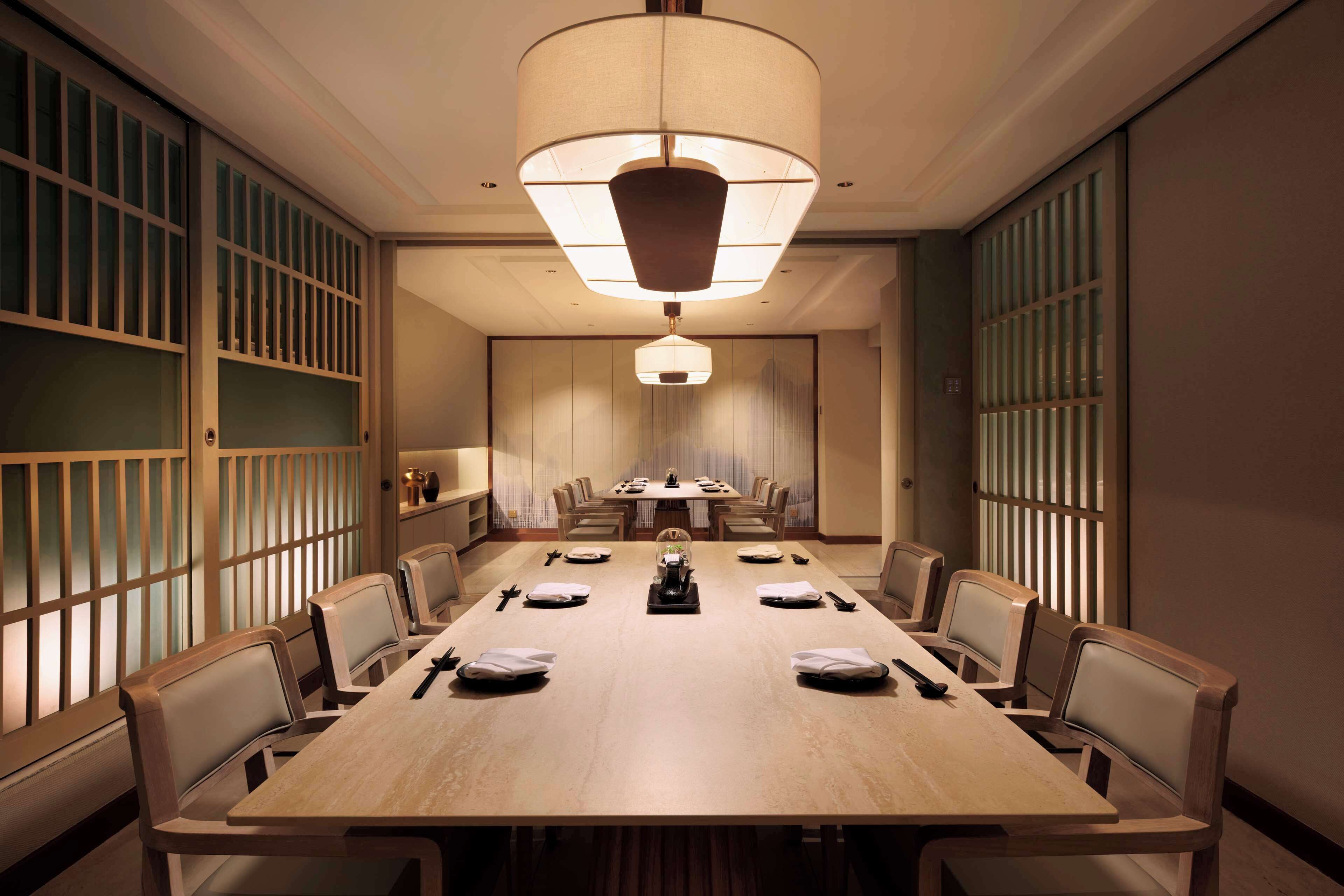 A conference room with a long table, chairs, and a hanging light fixture.