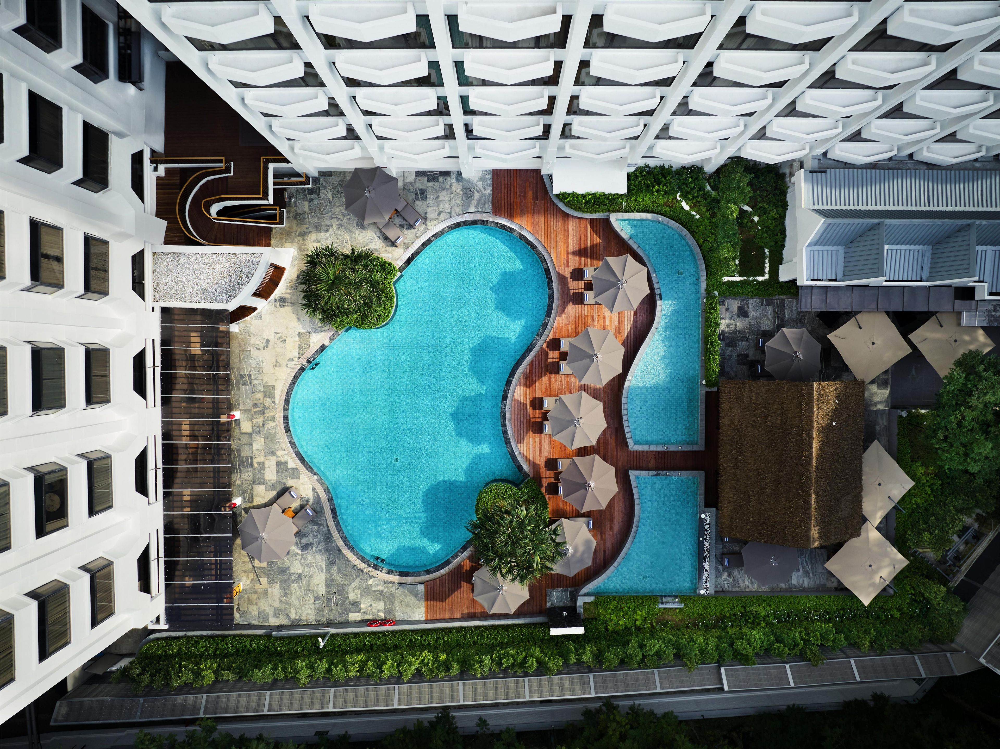 A rooftop swimming pool with multiple lanes, surrounded by lounge areas and greenery.