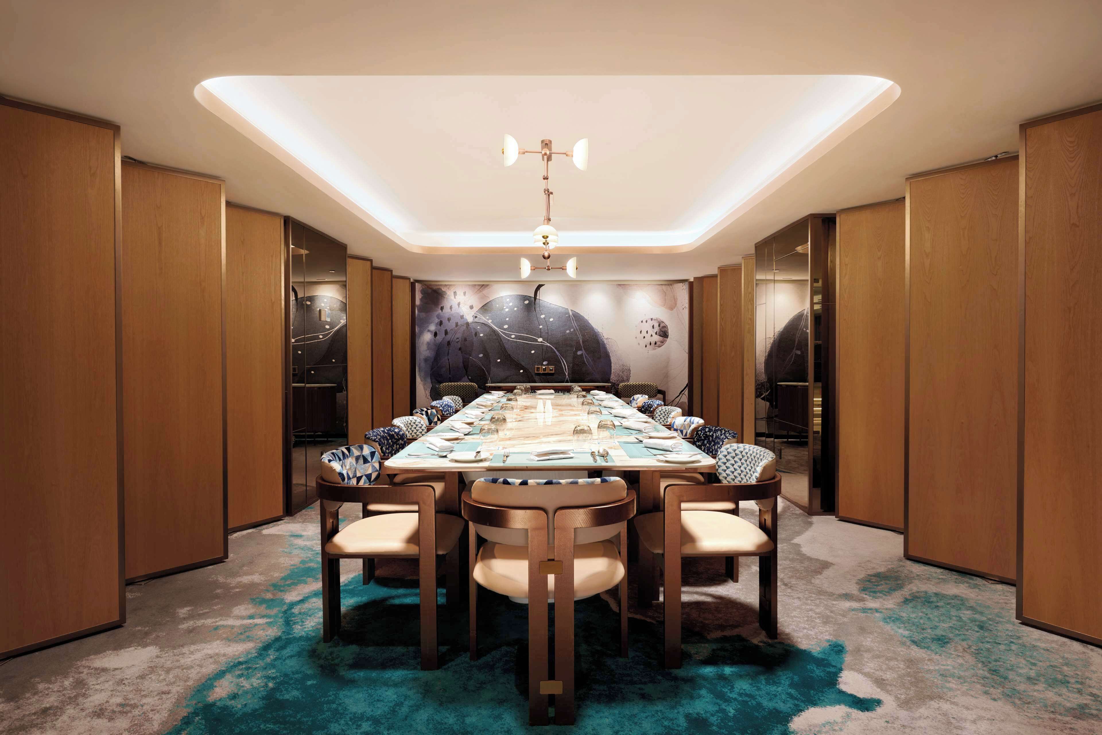 A conference room with a long table set for a meeting, surrounded by wooden paneling and a carpeted floor.