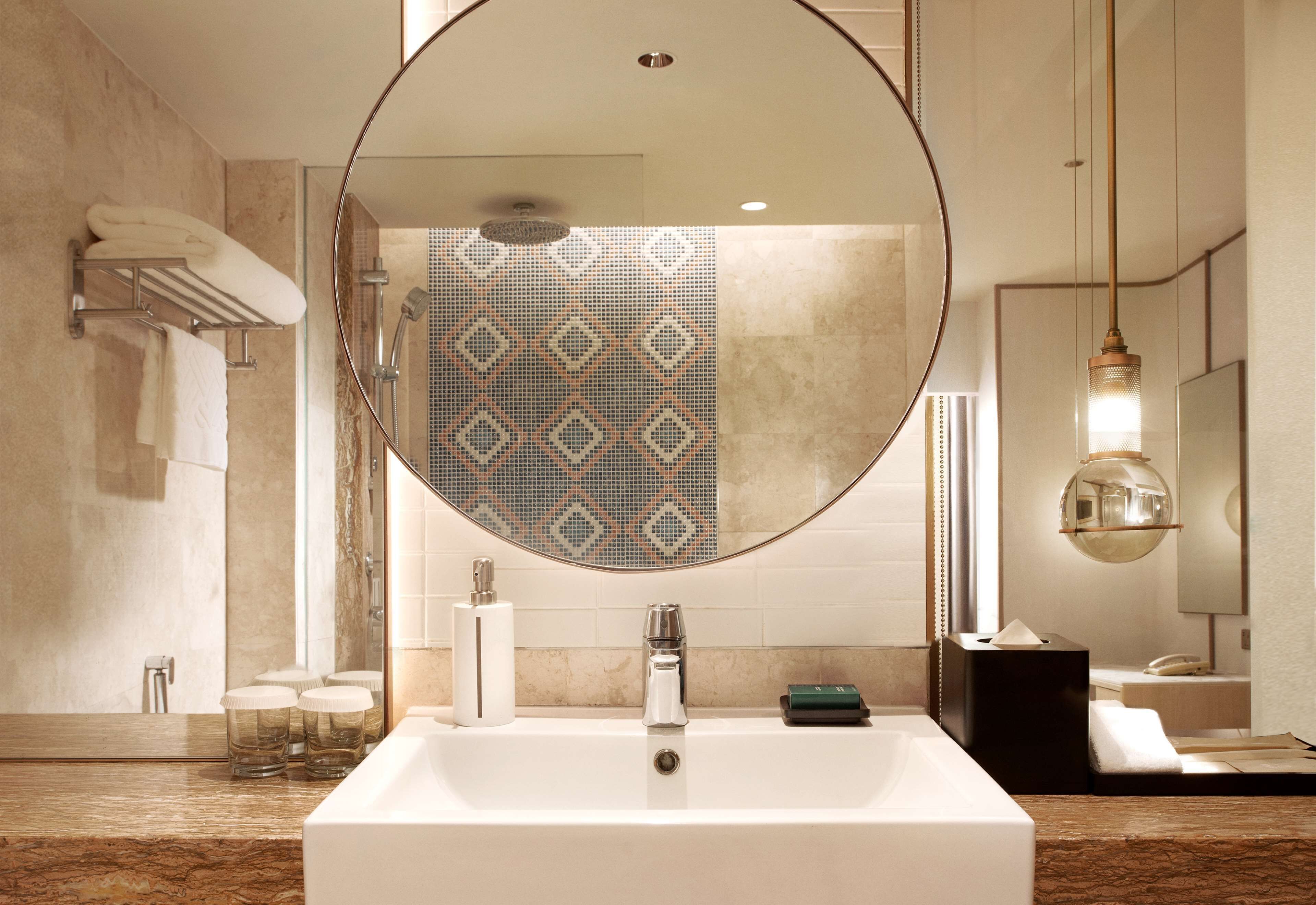 Un baño moderno con un espejo grande, un lavabo rectangular y una ducha.