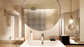 A modern bathroom with a large mirror, a rectangular sink, and a shower.