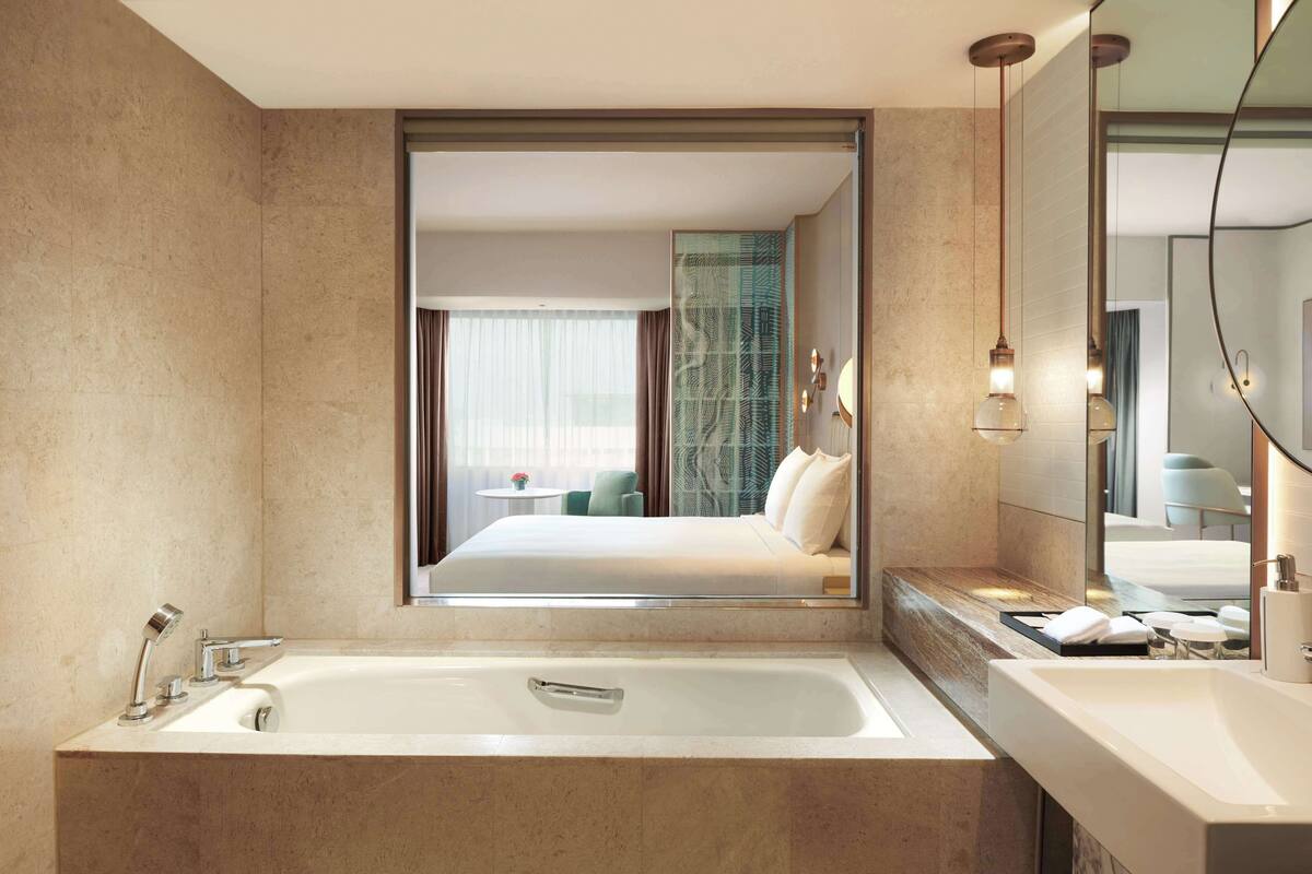 A modern bathroom with a large mirror, a bathtub, and a sink.