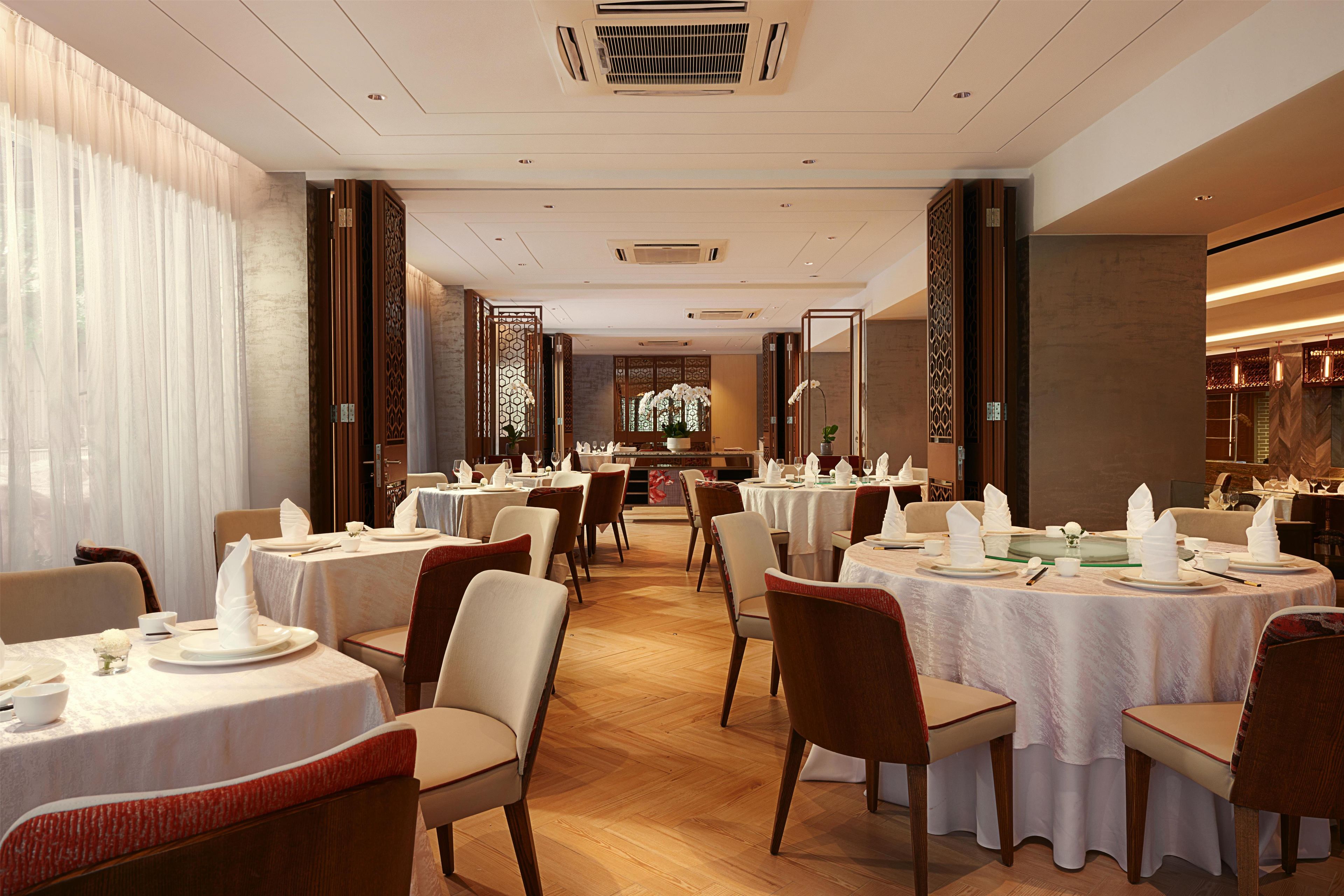 A restaurant with round tables, chairs, and a view of the interior.