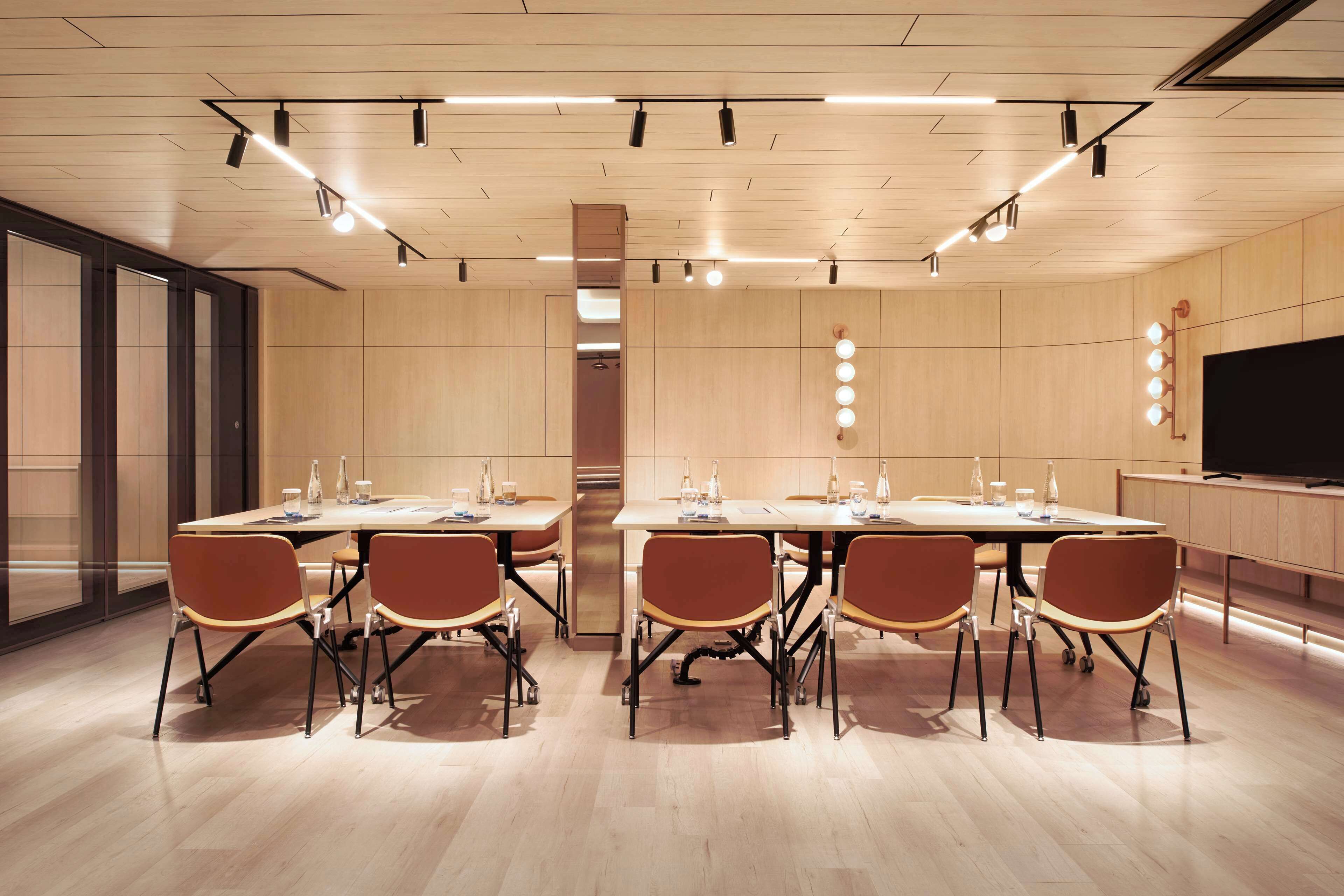 A conference room with a long table, six chairs, and a large screen.