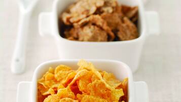 Tres tazones blancos de cerámica con asa, cada uno con distintos tipos de cereal.