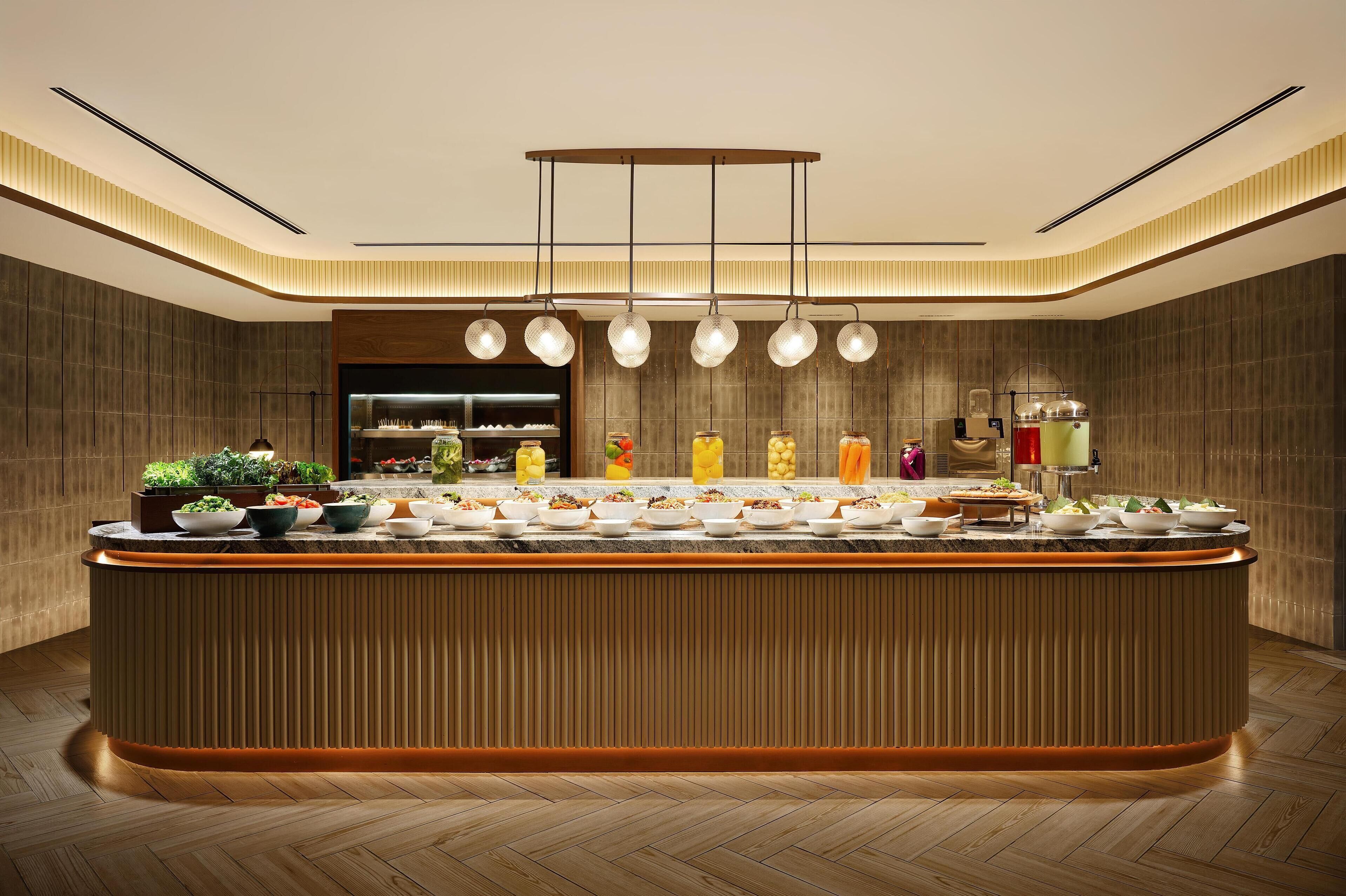A modern kitchen with a central island, pendant lighting, and a built-in refrigerator.