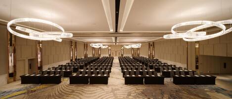 A spacious conference room with rows of black chairs and a patterned carpet.