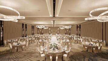 Un salón de banquetes con mesas redondas y sillas, candelabros y suelo alfombrado.