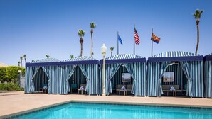 A poolside area with striped canopies, lounge chairs, and flags. - Tropicana Laughlin Hotel & Casino - A Caesars Rewards Destination (Laughlin)