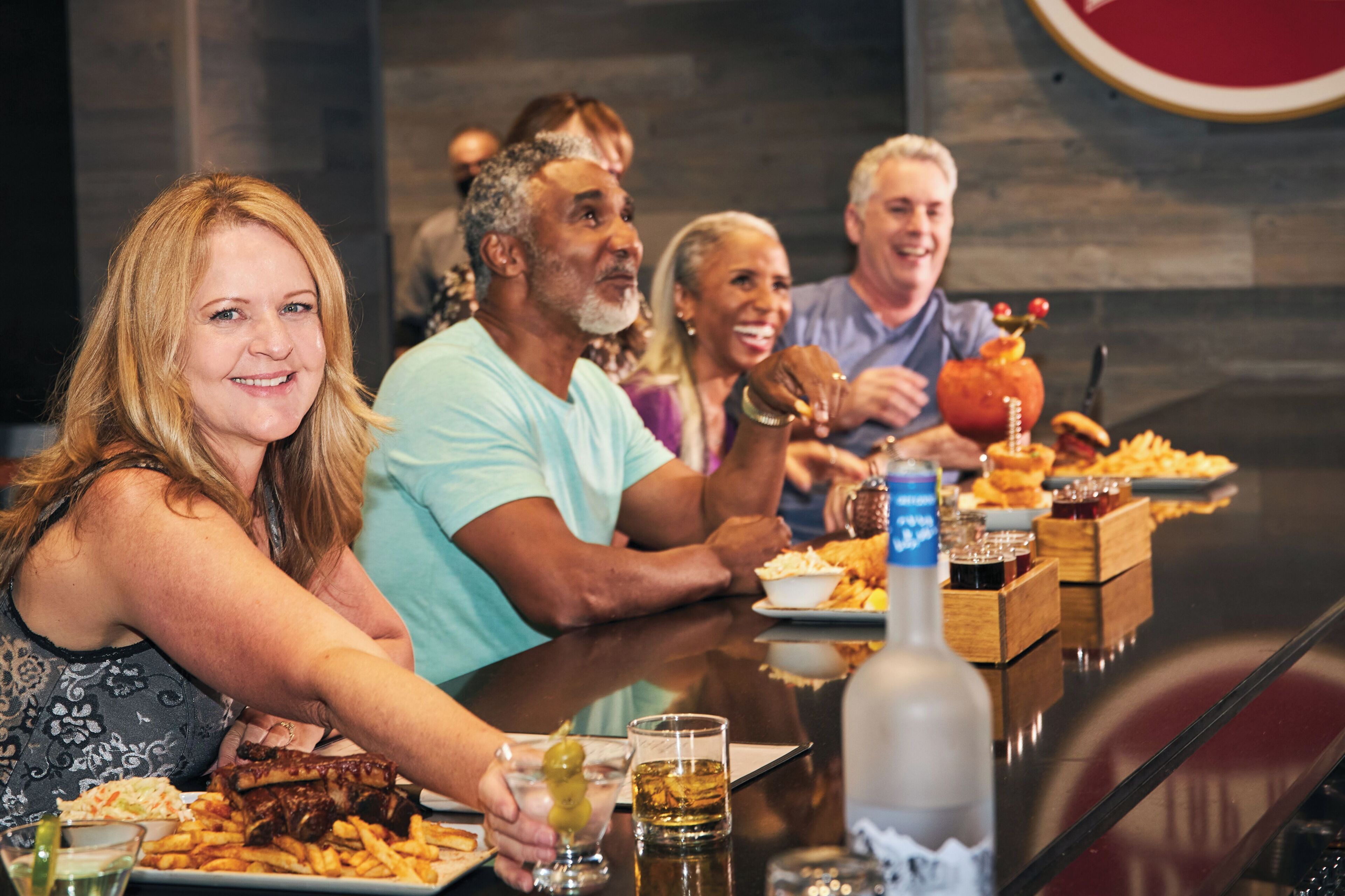 Un grupo de personas sentadas a una mesa con comida y bebidas.