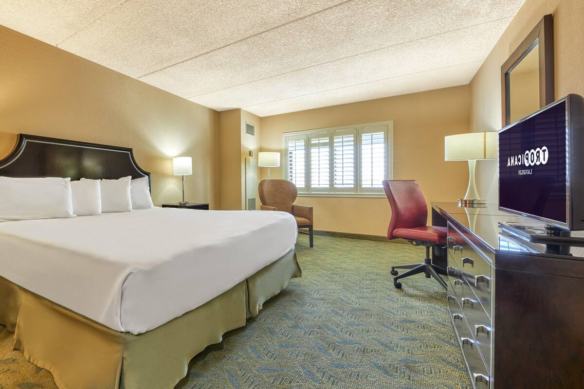 Une chambre d’hôtel avec un grand lit, un bureau équipé d’un ordinateur, une chaise et un téléviseur.