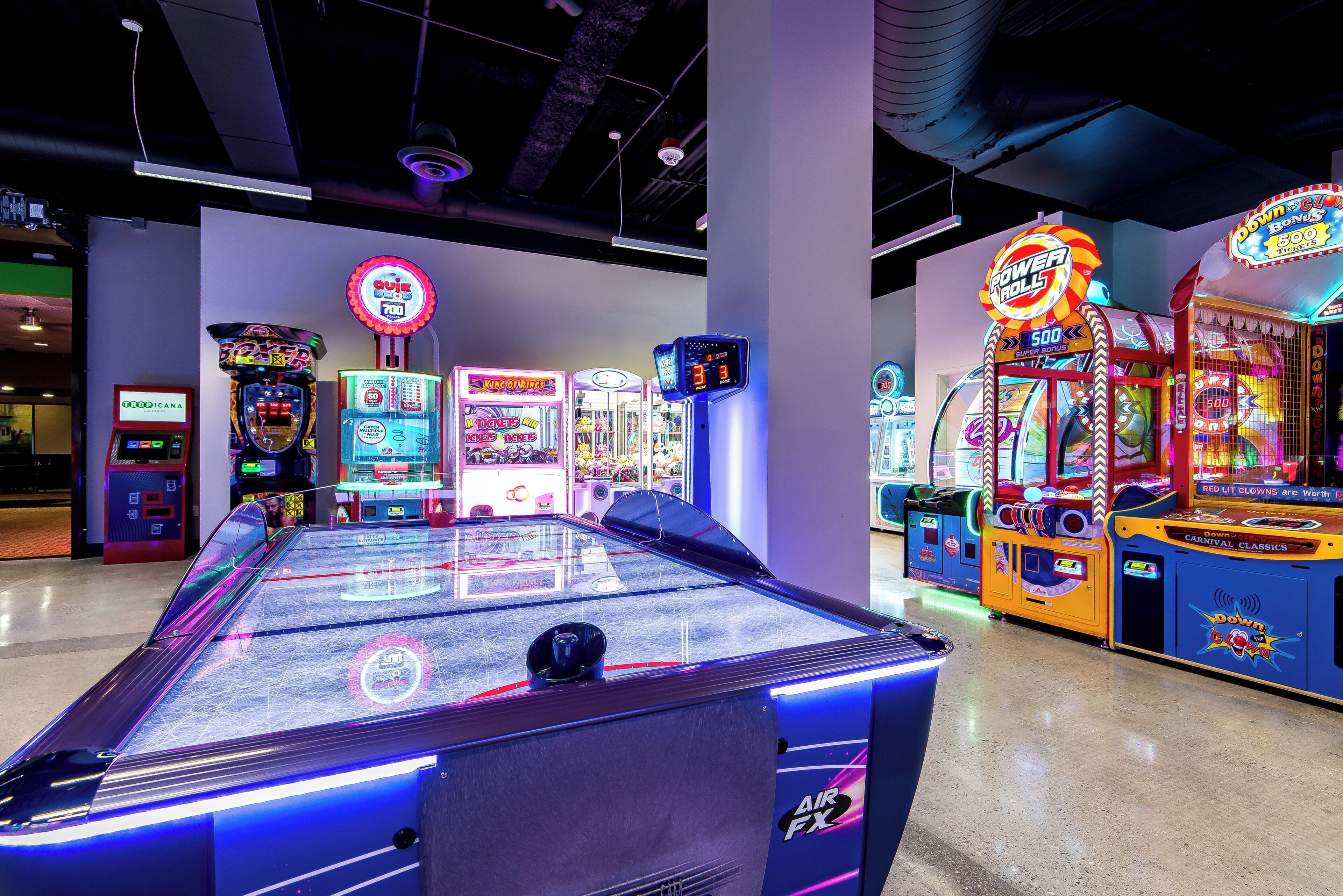 An indoor arcade with various gaming machines, including a pool table and claw machines.