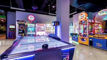 An indoor arcade with various gaming machines, including a pool table and claw machines.