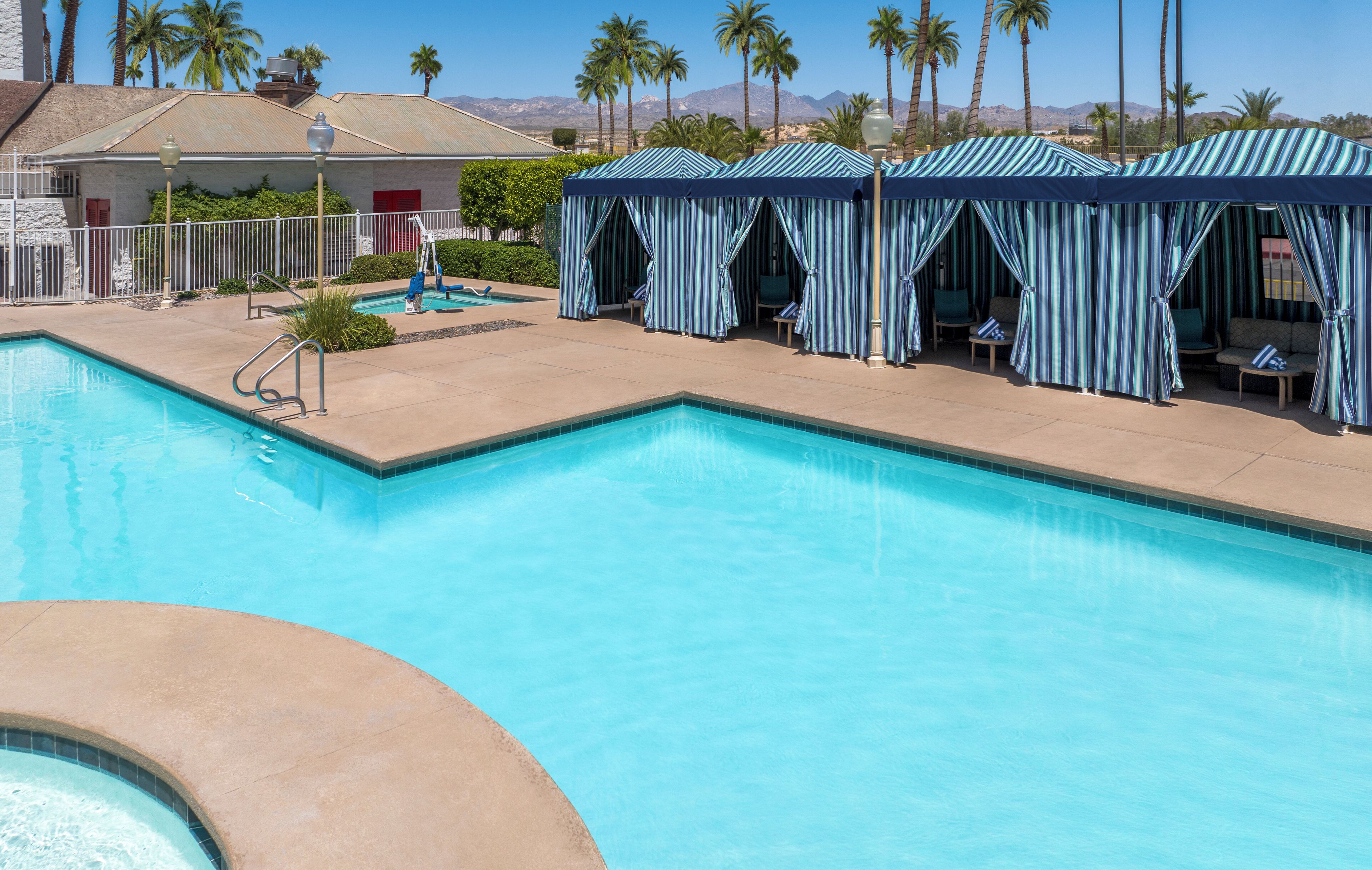 Une piscine dotée d’un espace de détente avec des parasols à rayures et des sièges.
