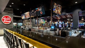 A bar area with multiple screens, a beer tap, and gaming machines. - Tropicana Laughlin Hotel & Casino - A Caesars Rewards Destination (Laughlin)