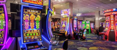 A casino with slot machines, gaming tables, and a patterned carpet.