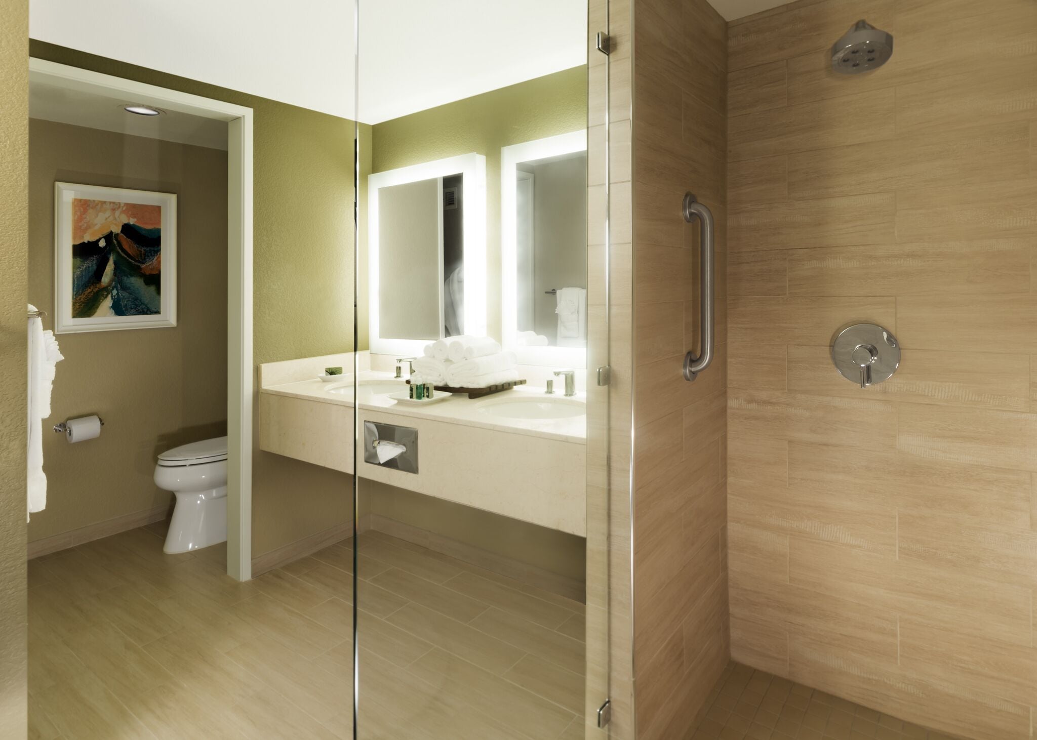 Un baño moderno con cabina de ducha de vidrio, inodoro, lavabo con espejo y toallero.
