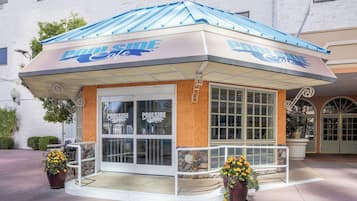 Ein Poolside-Café mit blauem Dach und weißer Fassade, mit großen Fenstern und einer Wand aus Stein.