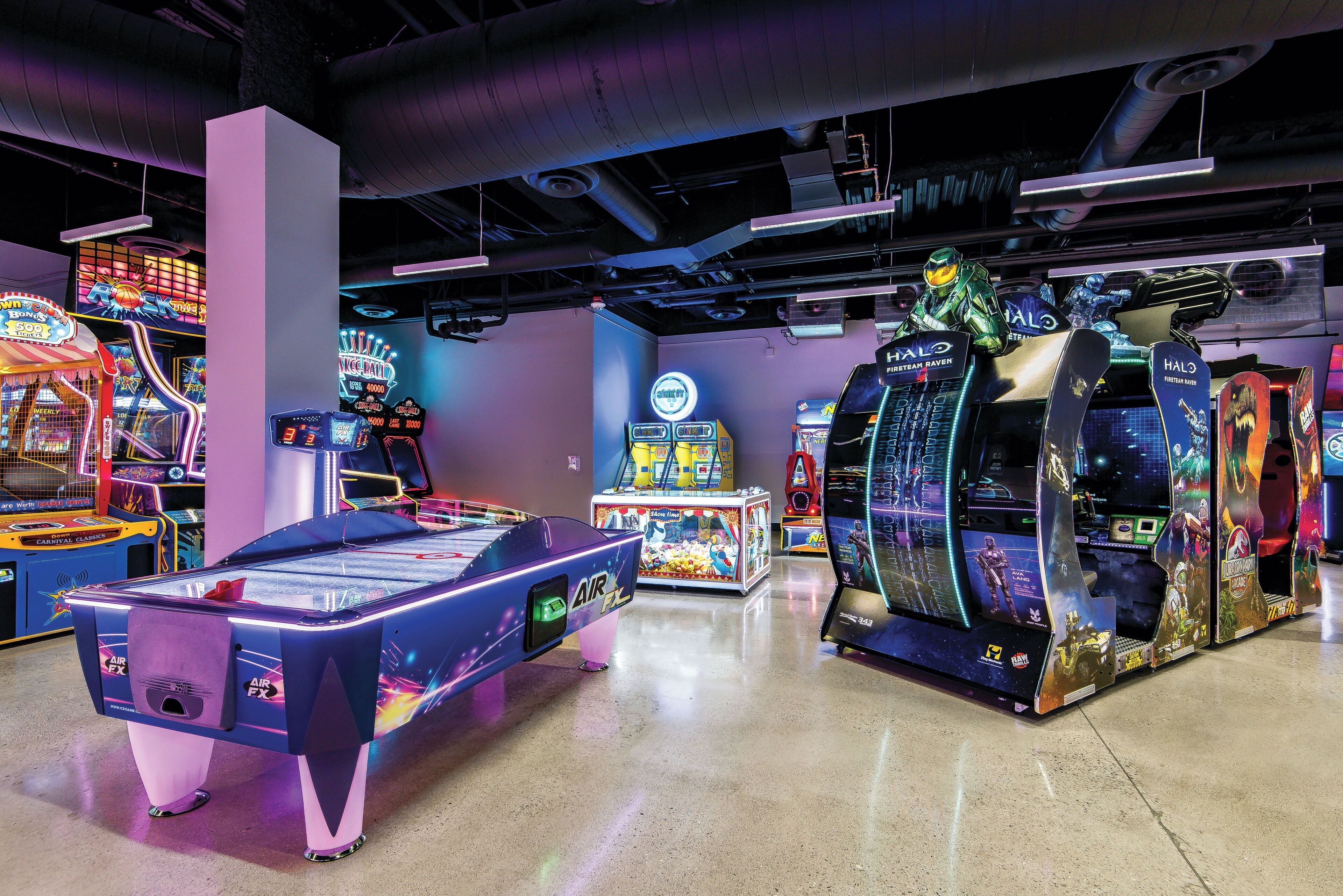 Une salle d’arcade intérieure proposant divers jeux, notamment un billard et une borne d’arcade sur le thème de Halo.