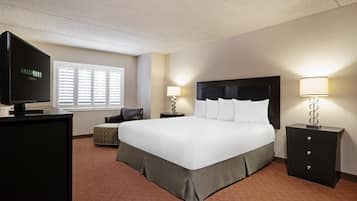 A hotel room with a large bed, a TV, a desk, and a chair.