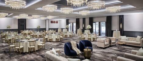 Un amplio vestíbulo de hotel con varias zonas de comedor, elegantes candelabros y cómodos asientos.