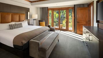 Habitación de hotel con una cama grande, un sofá, un escritorio y un balcón con vistas a árboles.