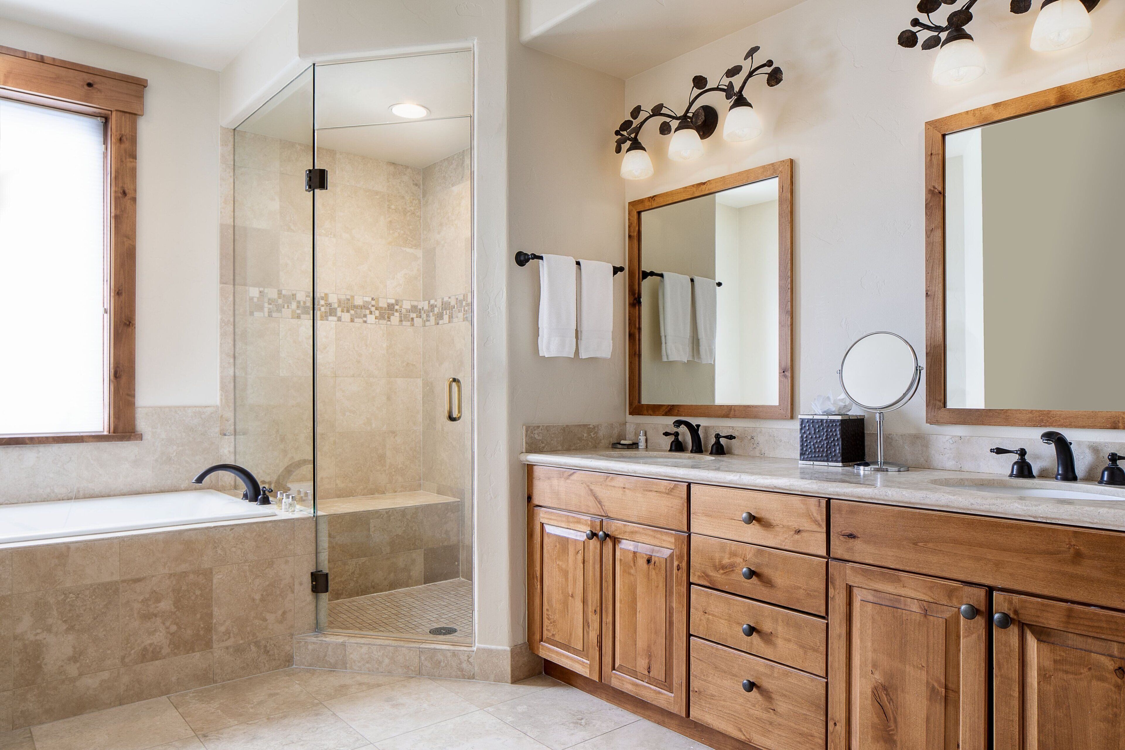 Une salle de bain moderne dotée d’une douche à parois de verre, d’un meuble-lavabo en bois et de deux miroirs.