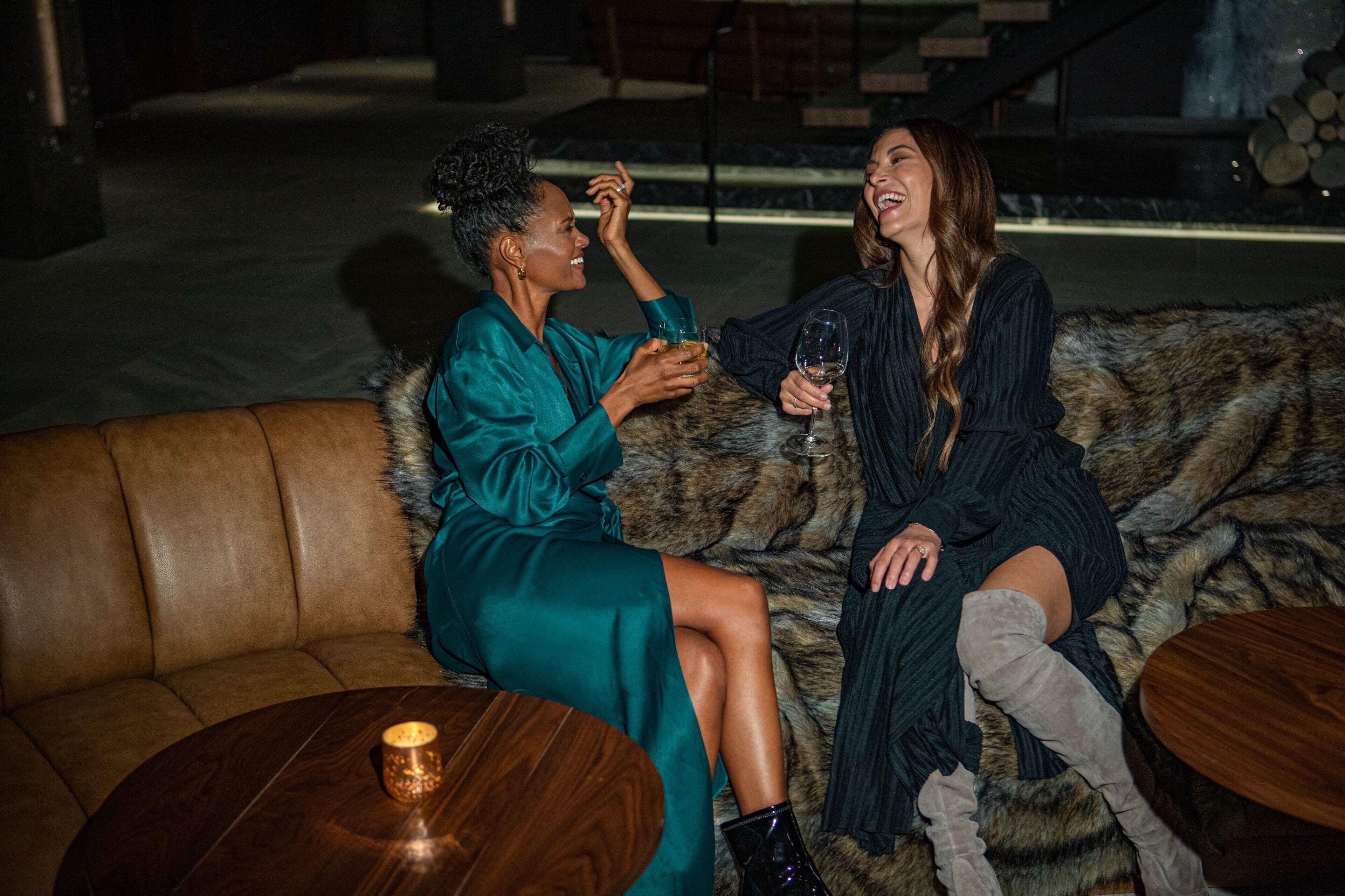 Two people sitting on a fur-covered couch with a wooden table in front of them.