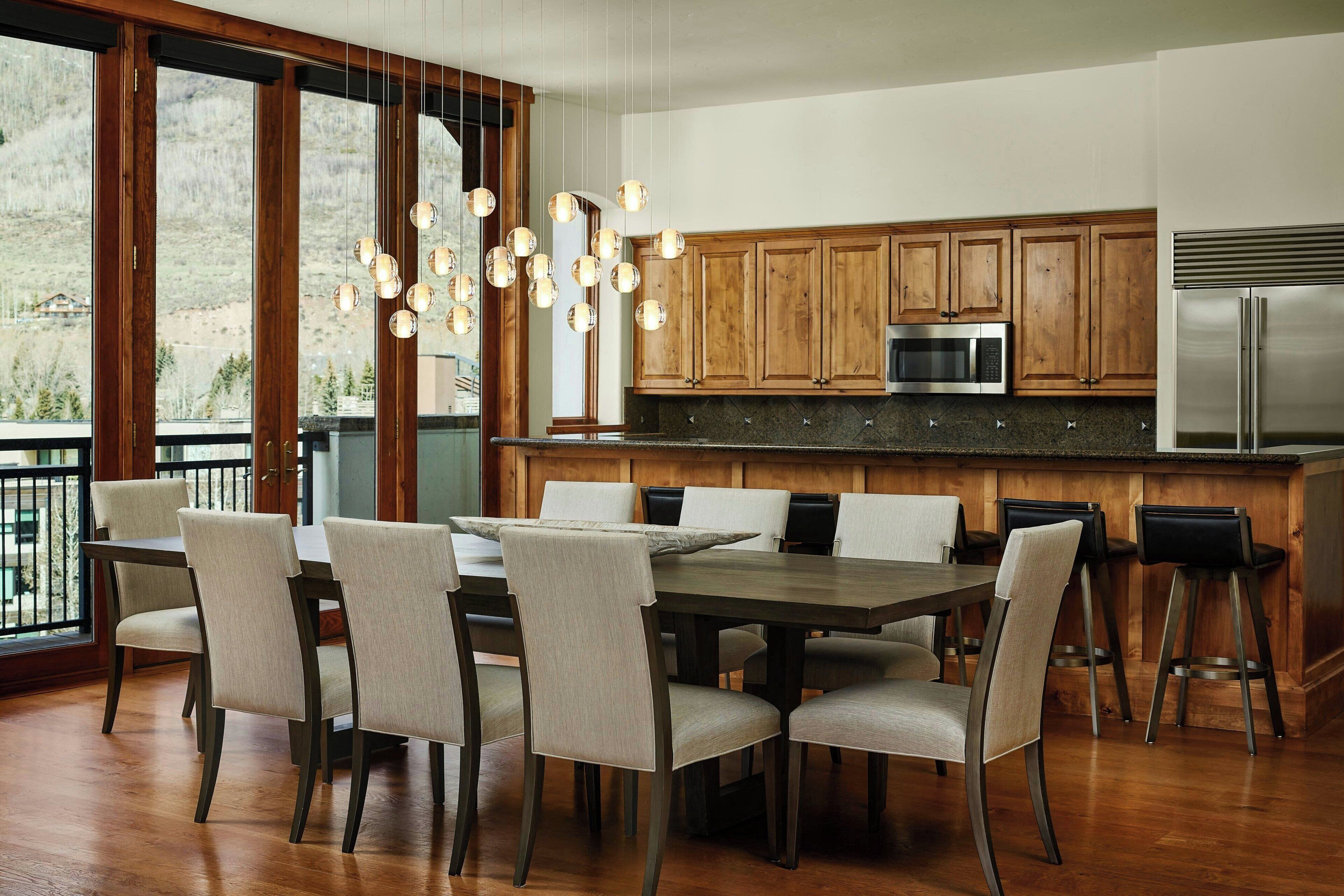 Eine moderne Küche mit Holzausstattung, einem Edelstahlkühlschrank und einem Essbereich mit Tisch und Stühlen.