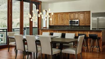 A modern kitchen with wooden cabinets, a stainless steel refrigerator, and a dining area with a table and chairs.