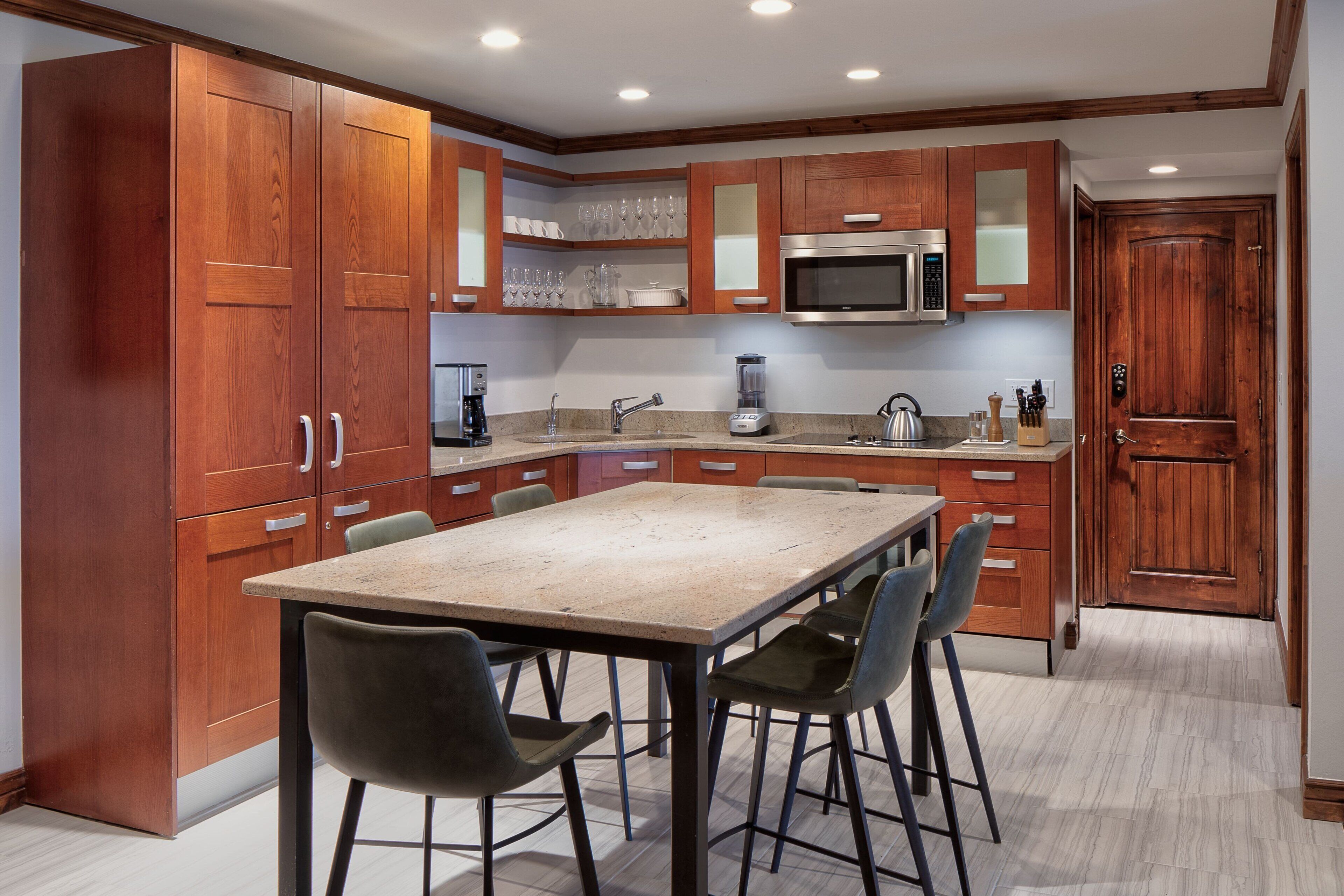 A modern kitchen with wooden cabinets, a stainless steel microwave, and a granite countertop.